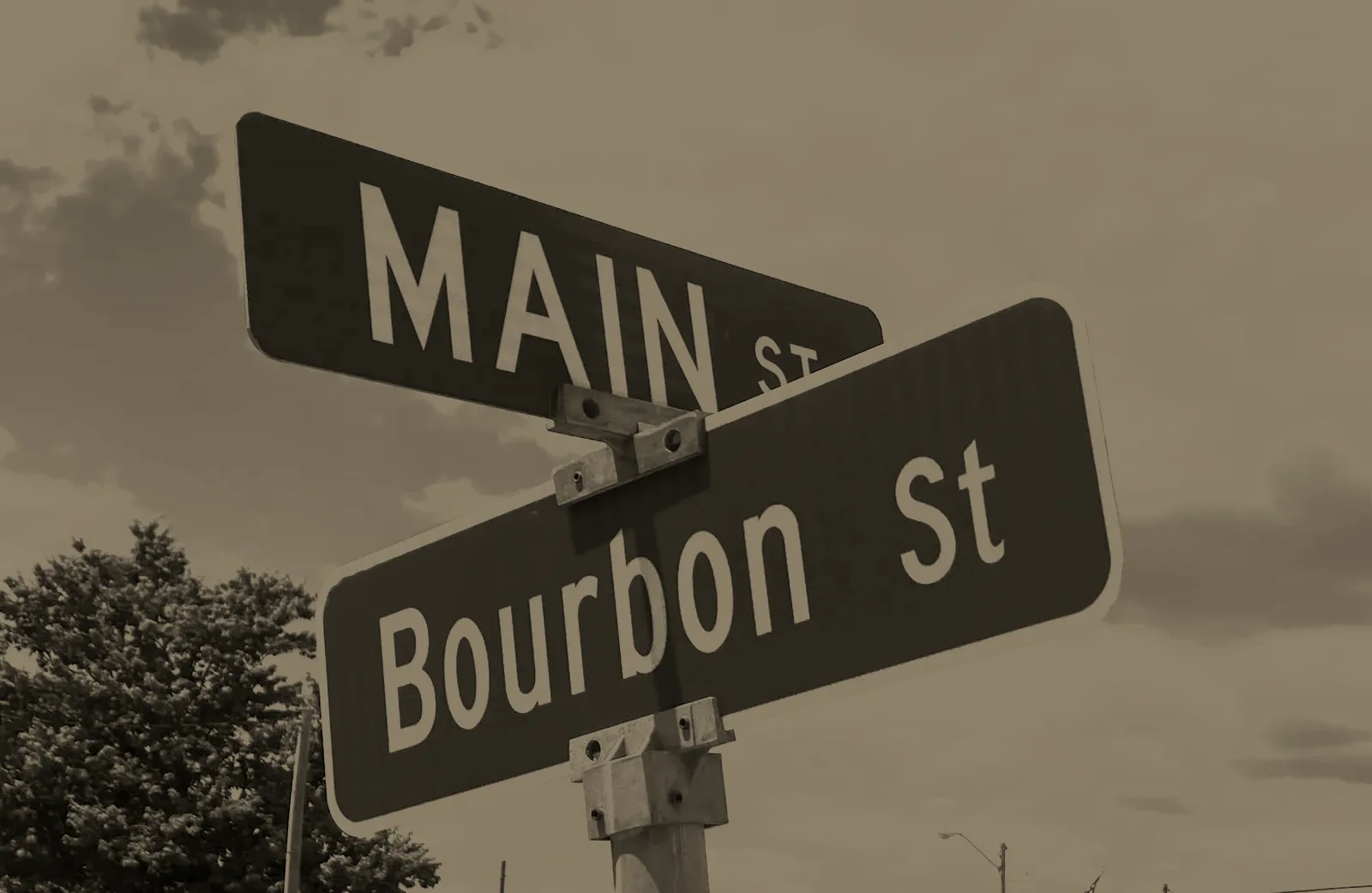 The Bourbon Street and Main Street signs at the corner, in sepia