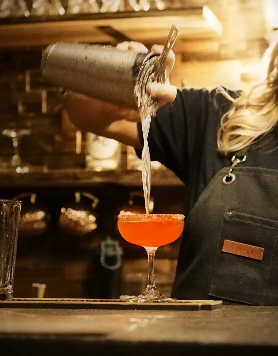 A Flapper's Fringe being poured from the shaker into a sugar-rimmed coupe