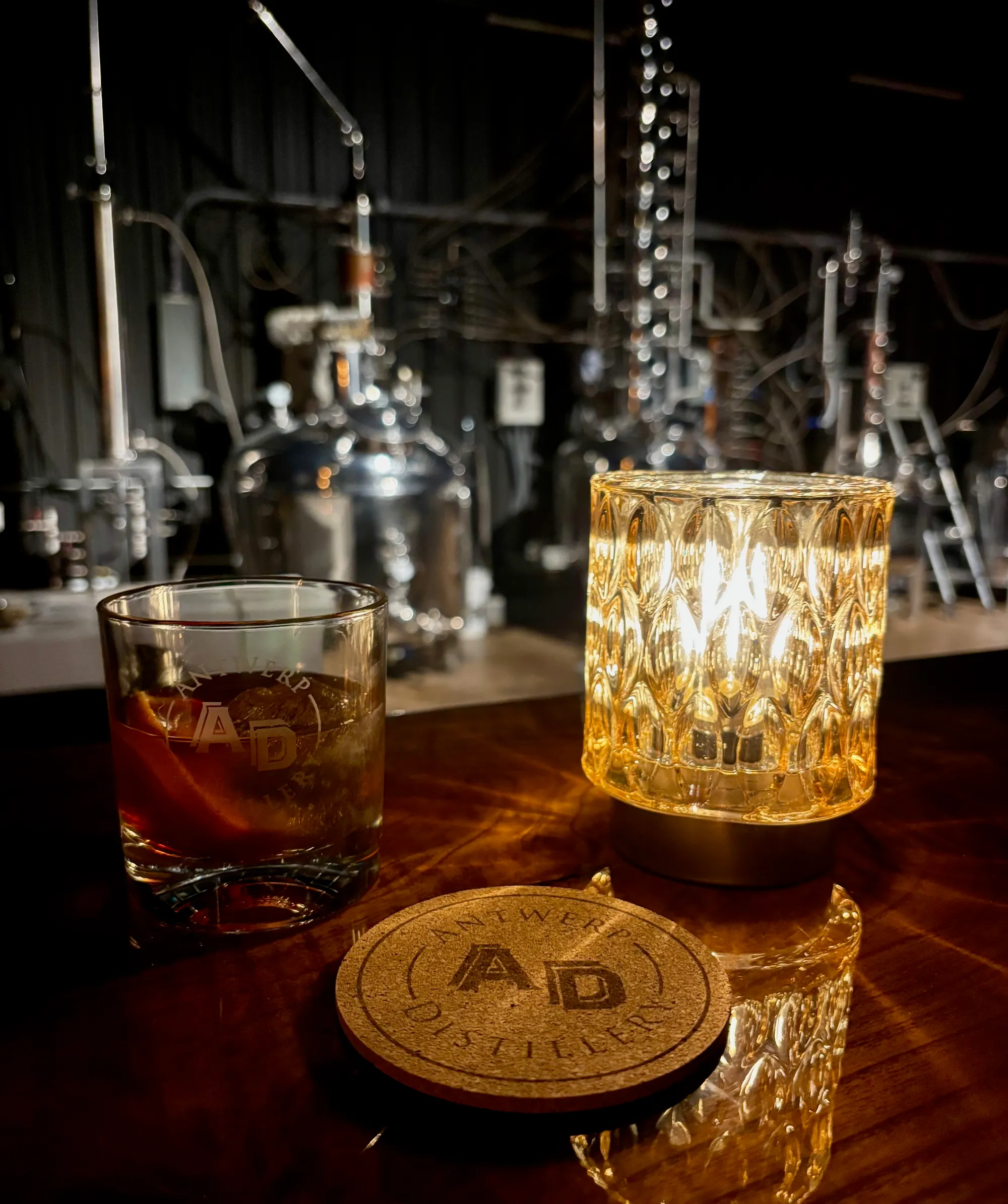 Branded whiskey glass with distillery stills in background