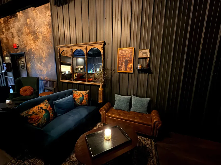 A speakeasy seating nook — velvet sofa and an ornate mirror
