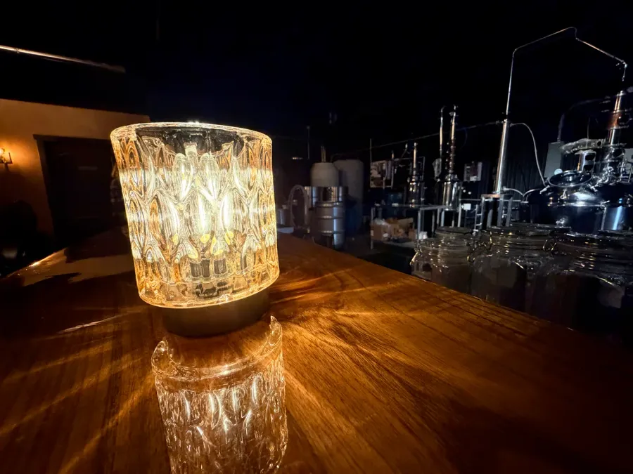 A crystal prism sconce glowing amber on the lounge bar top