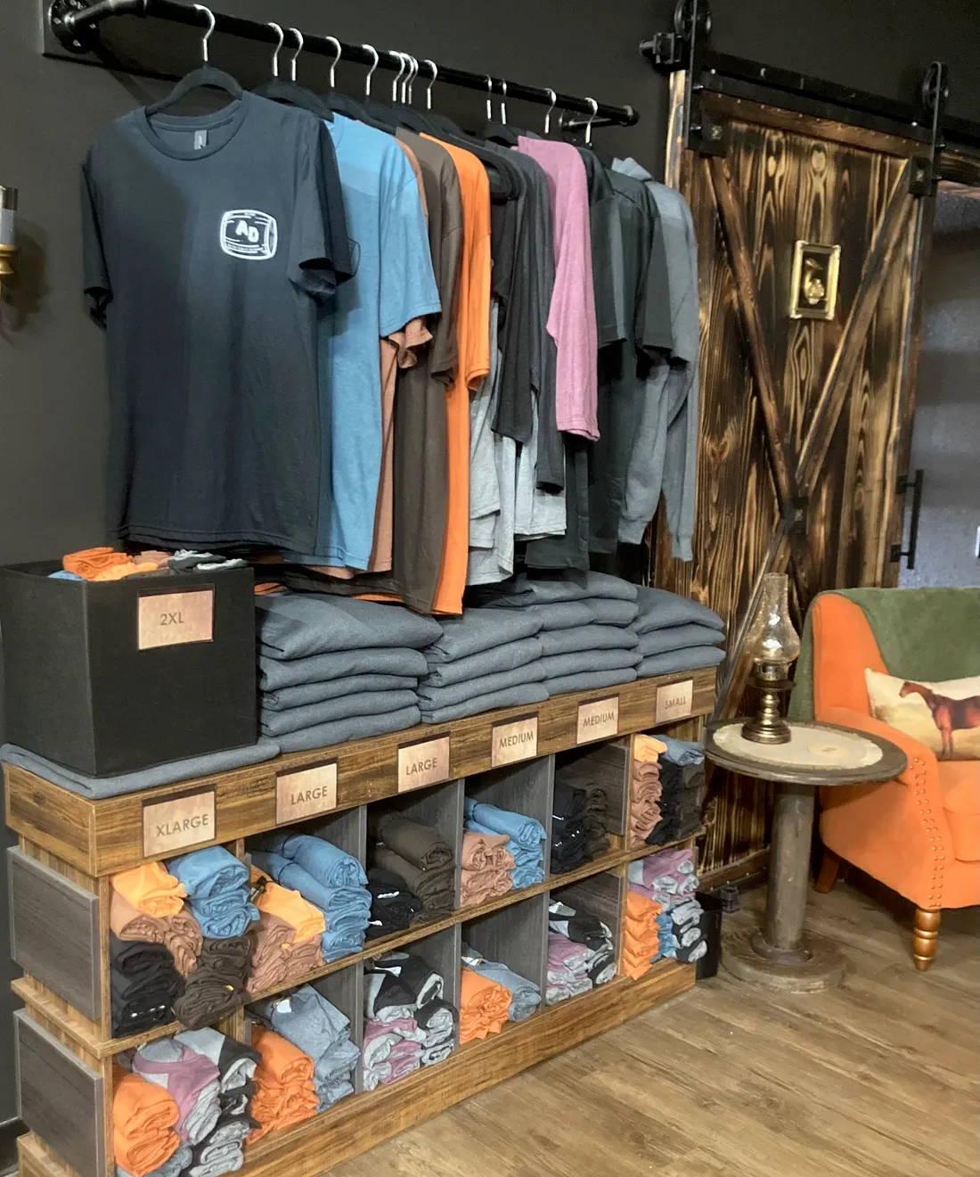Embroidered Antwerp Distillery tees stacked on reclaimed-wood shelves