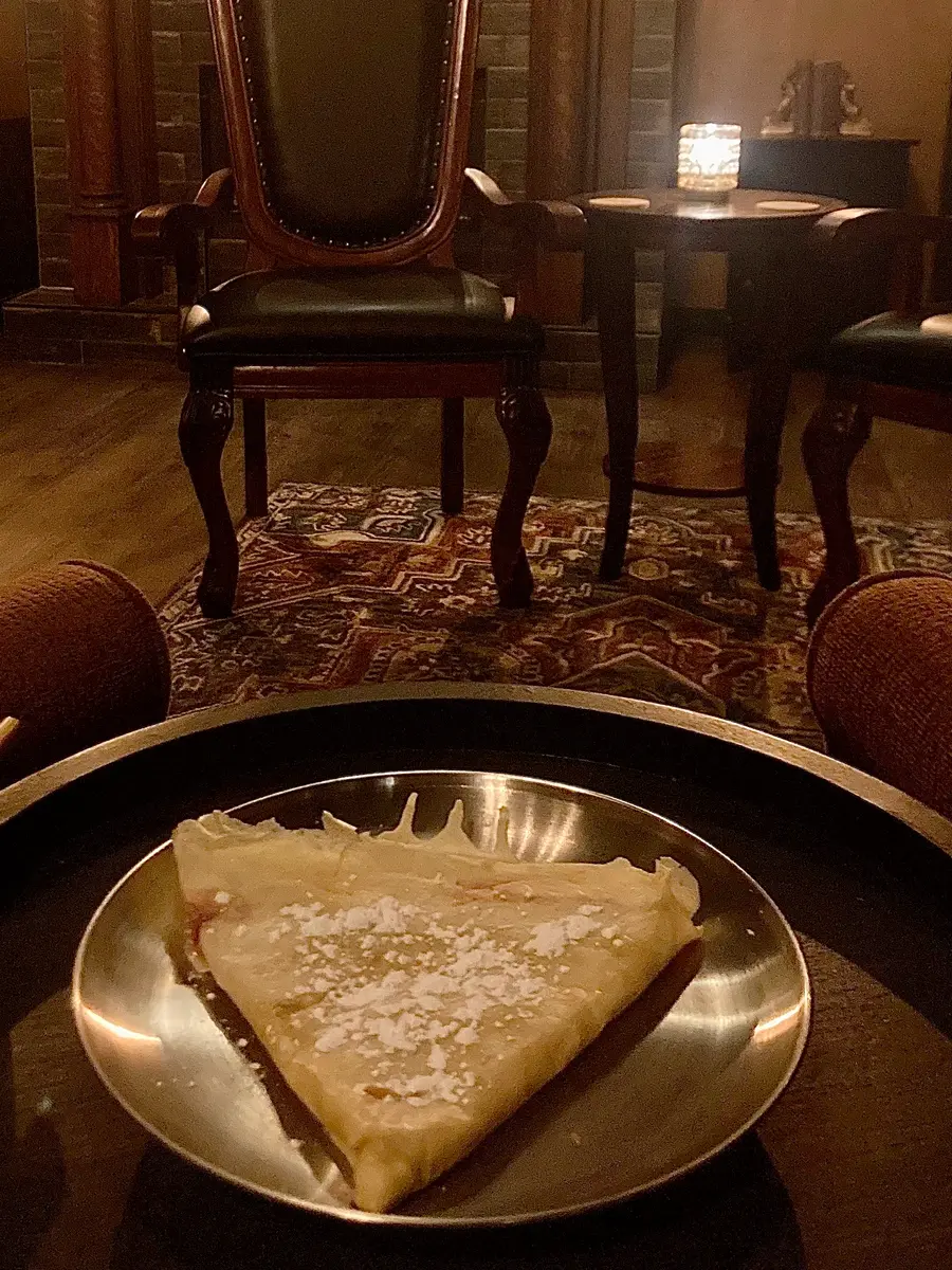 A house crepe dusted with powdered sugar, served in the speakeasy lounge